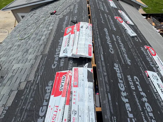 Shingle bundles staged along a stripped roof with the crew working at the ridge.
