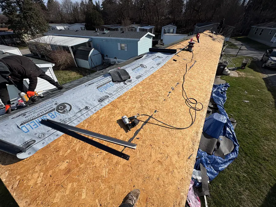 A roof stripped to new plywood decking with underlayment being run along the edge.