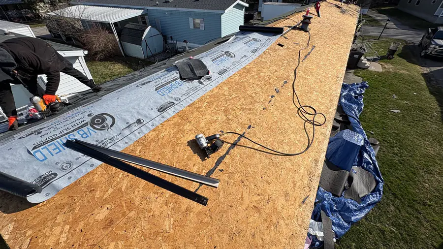 A roof stripped to new plywood decking with underlayment being run along the edge.