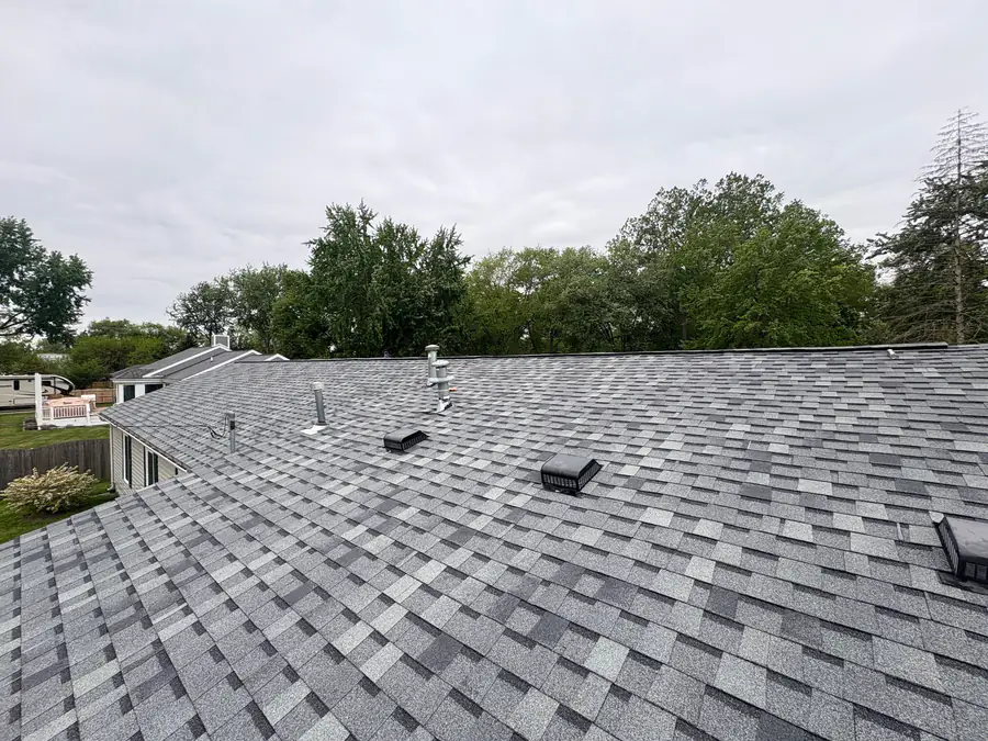A wide finished grey shingle roof with ridge vent, seen from the peak.