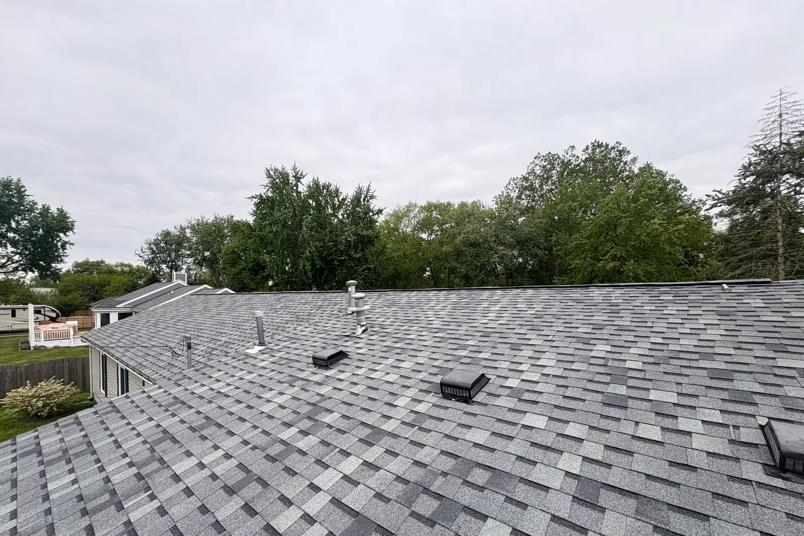 A wide finished grey shingle roof with ridge vent, seen from the peak.