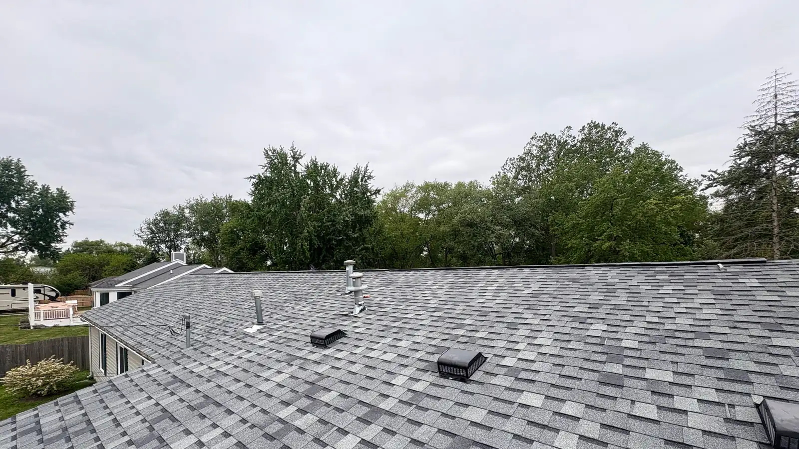 A wide finished grey shingle roof with ridge vent, seen from the peak.