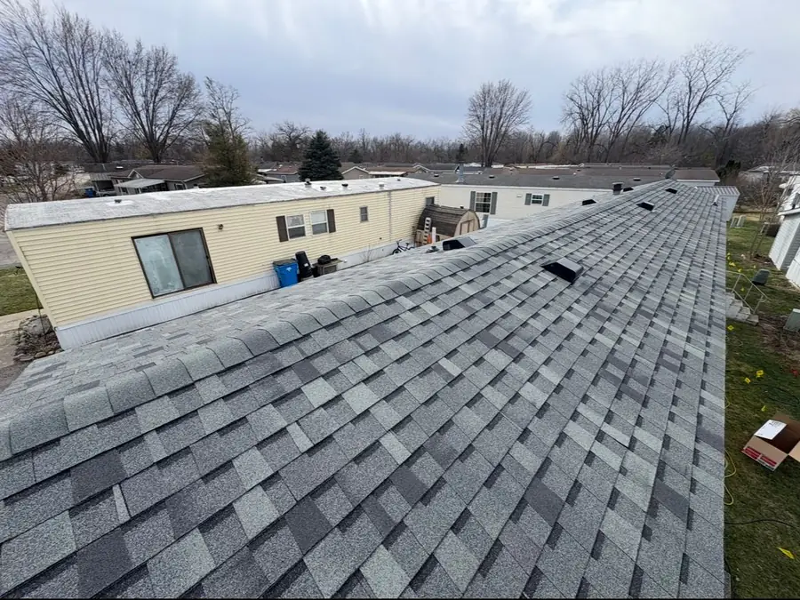 A long grey shingle roof on a manufactured home, finished and swept clean.