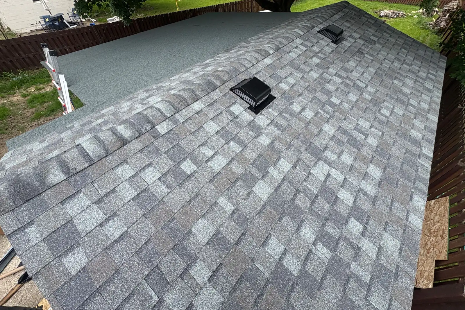 A finished grey architectural shingle roof with a roof vent and skylight.