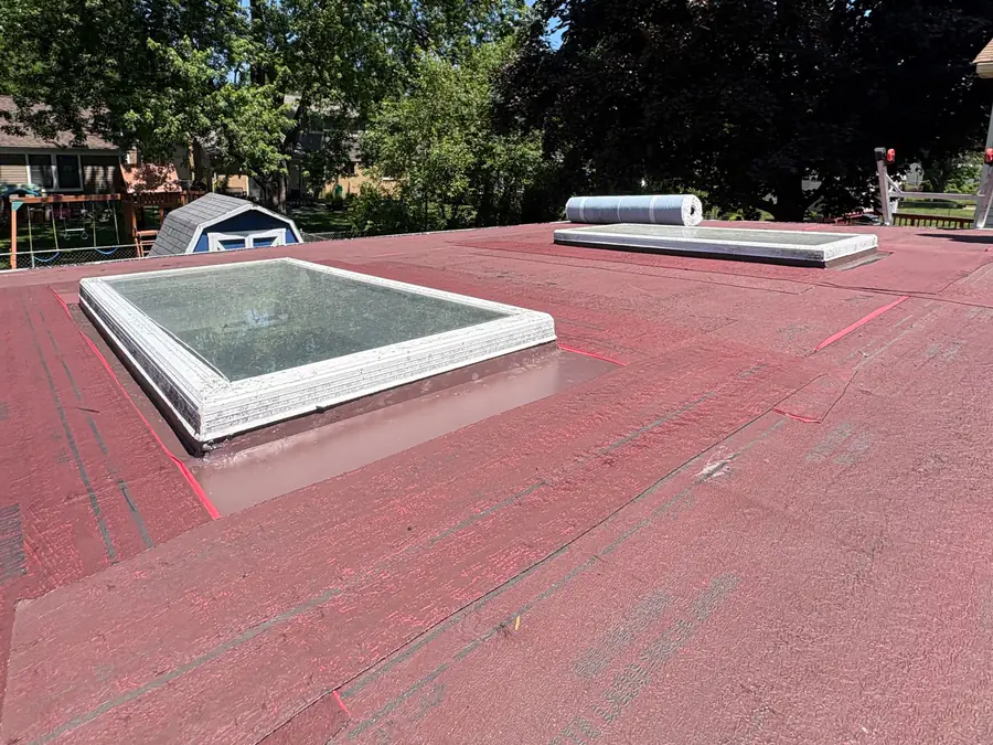 Two skylights set into a low-slope roof covered in red underlayment.